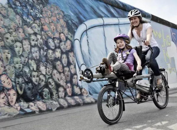 Kindje vooraan op aangepaste fiets met mama die trapt