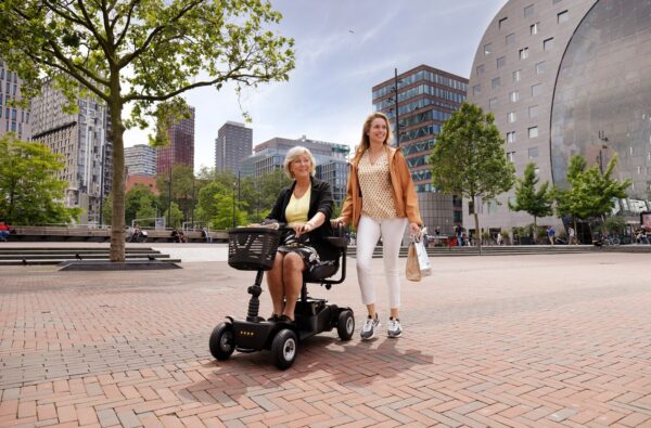 Vrouw met scooter in stad samen met jongere stappende vrouw