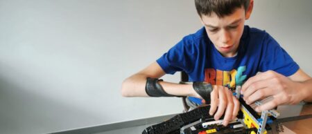 Jongen draagt de 4D-handorthese en speelt met Lego